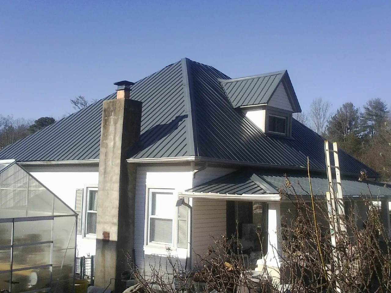 Dark blue standing seam metal roof on a white farmhouse with dormer — Slate & Tile Roof Repair by Roofing Brothers in Stockett