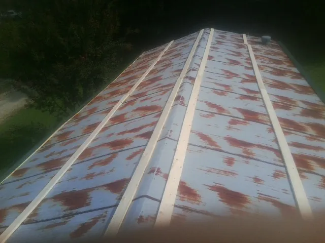 Rusted metal roof panels with new wood purlins before replacement — Storm Damage Roof Repair in Stockett by Roofing Brothers