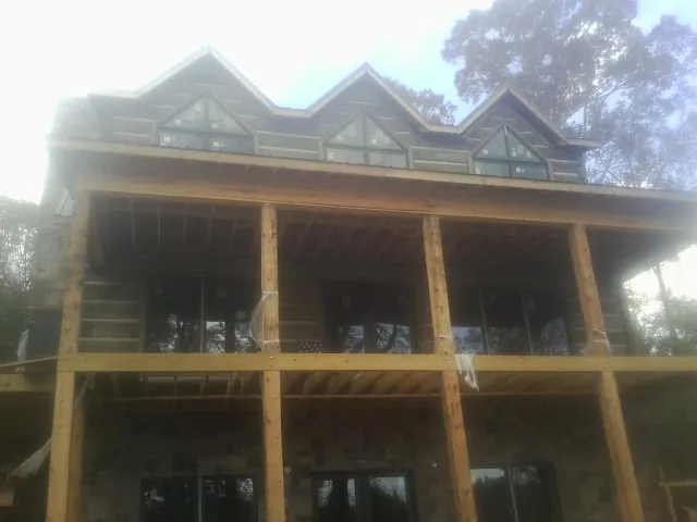 Dormers and porch framing on a large log home under construction — Roof Coating work by our crew in Stockett