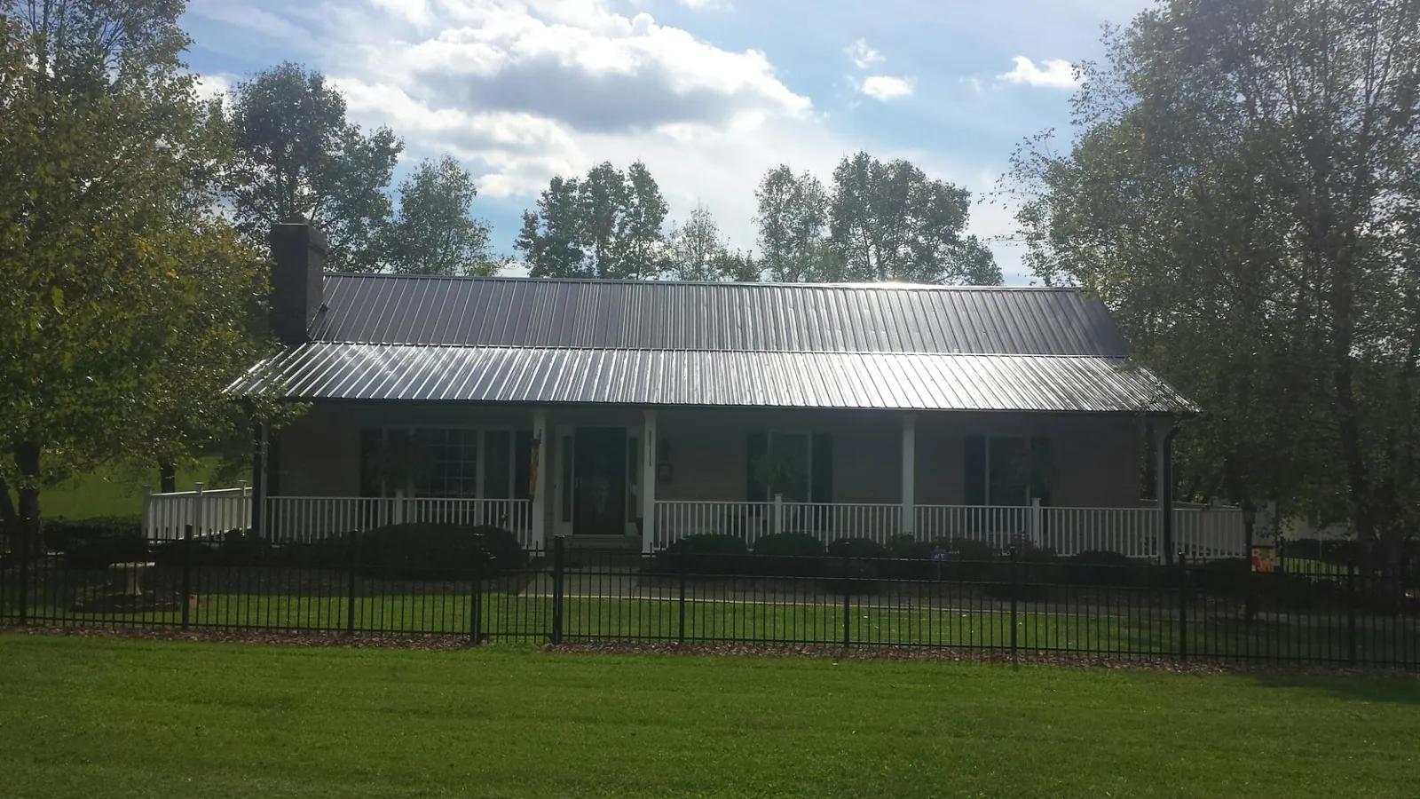 Gray metal roof on a brick ranch with a full width front porch — Gutter Guard Installation work by our crew in Stockett