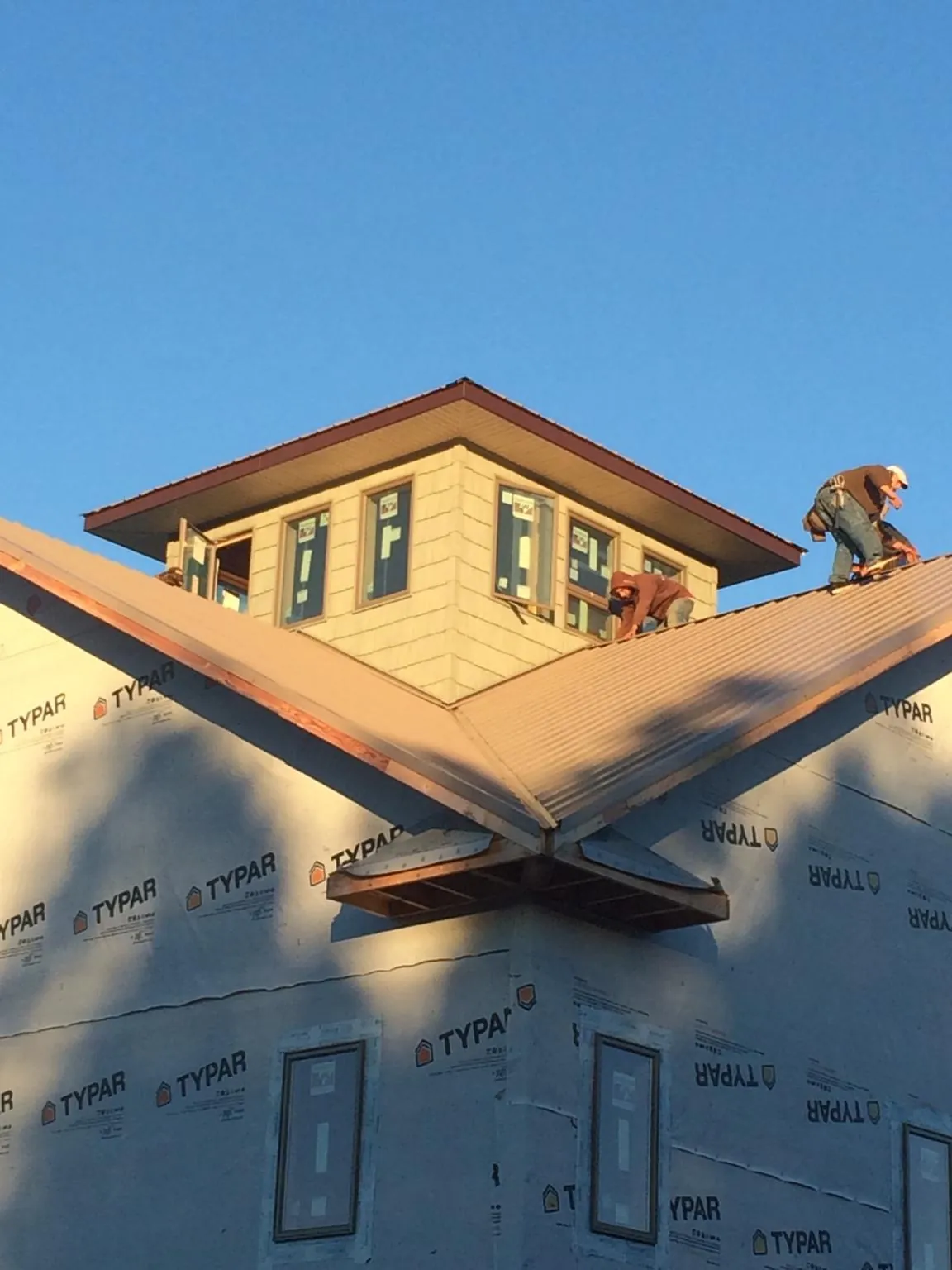 Roofers working around a rooftop cupola on a new metal roof at sunset — Roof Waterproofing in Stockett by Roofing Brothers